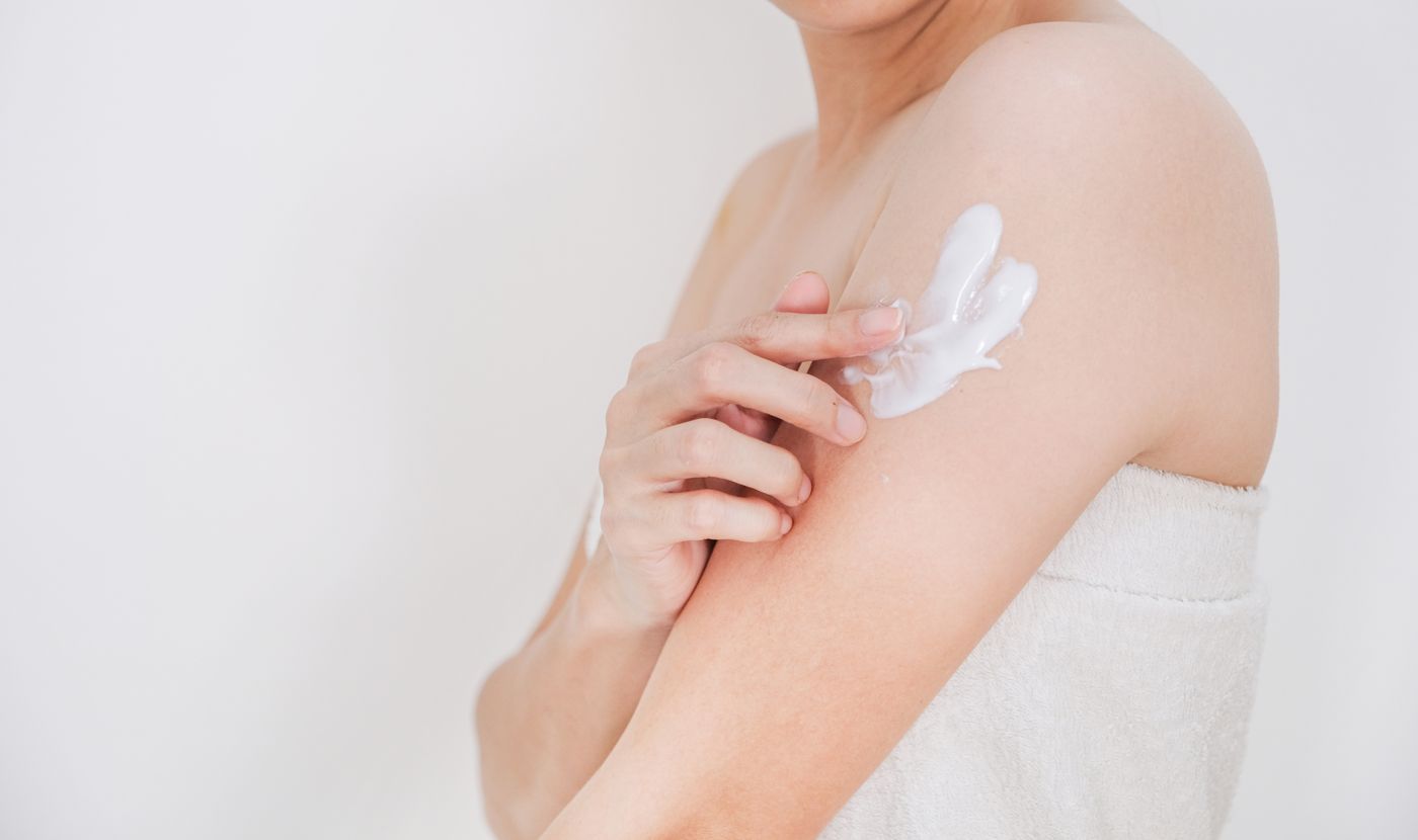 Woman applying cream to her upper arm