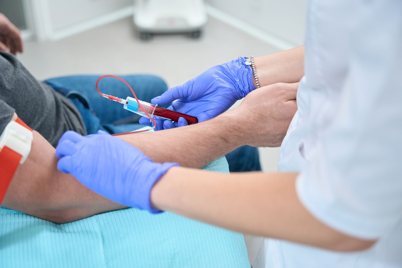Provider in blue gloves drawing a blood sample from a patient's arm