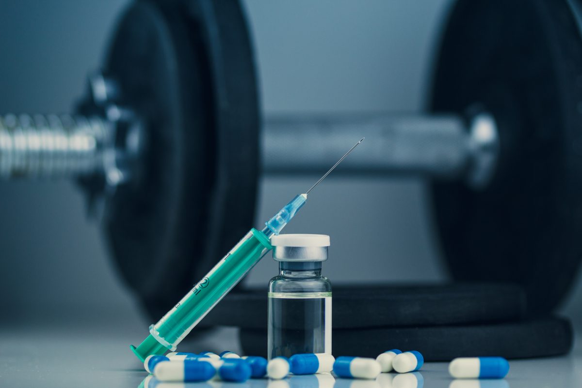 Syringe and vial beside a dumbbell, representing testosterone injection options